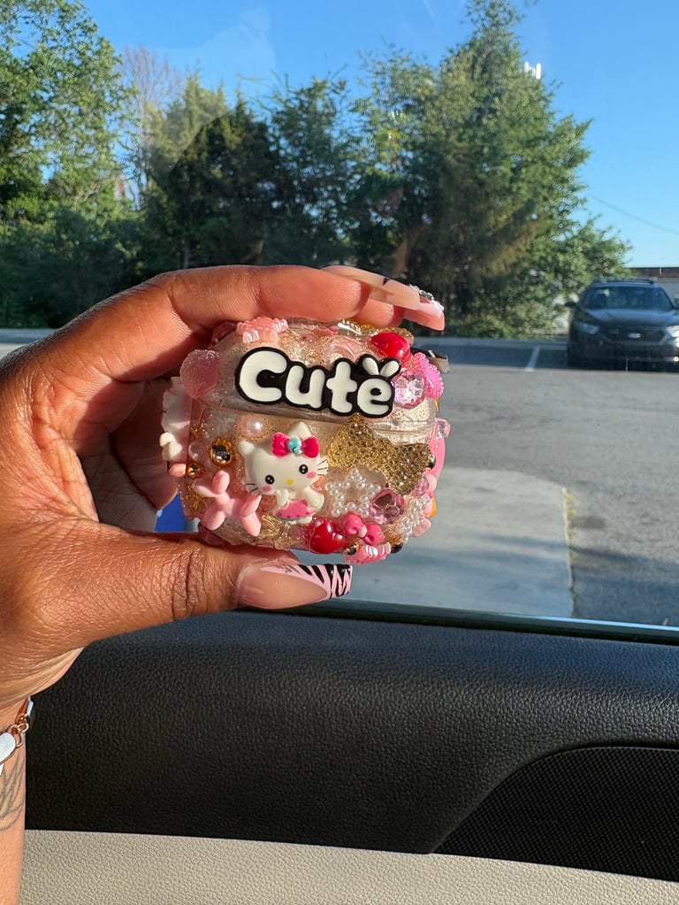 Hand holding a pink decorative item with Hello Kitty character, sequins, and cute text inside a car