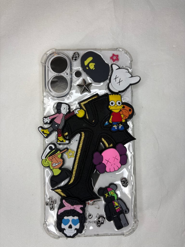 Clear phone case with colorful cartoon character charms and patches including a black cross design and pink cloud decoration