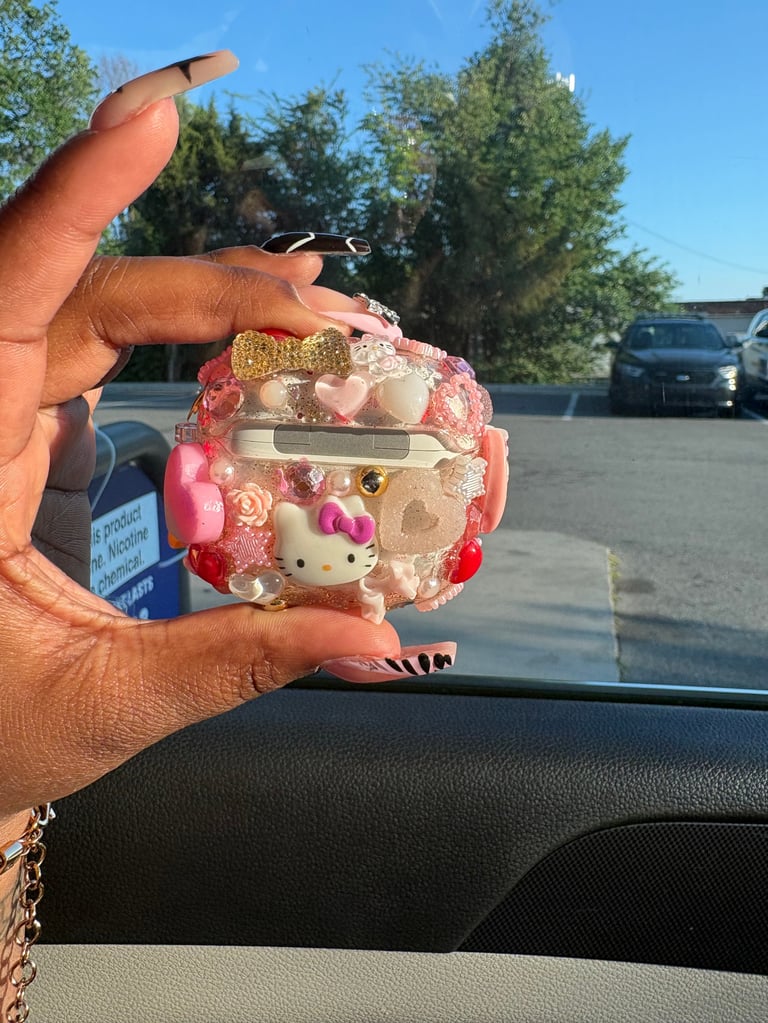 Person holding a pink decorative Hello Kitty-themed purse with floral embellishments in a car parking lot